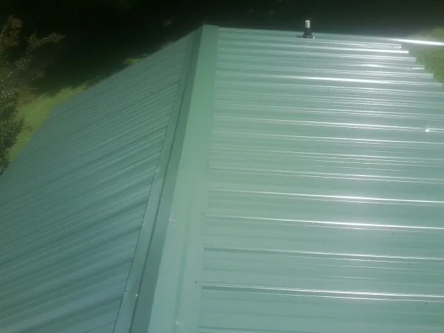 New green metal panels meeting at the ridge of a roof — Flat Roof Repair work by our crew in Wasco