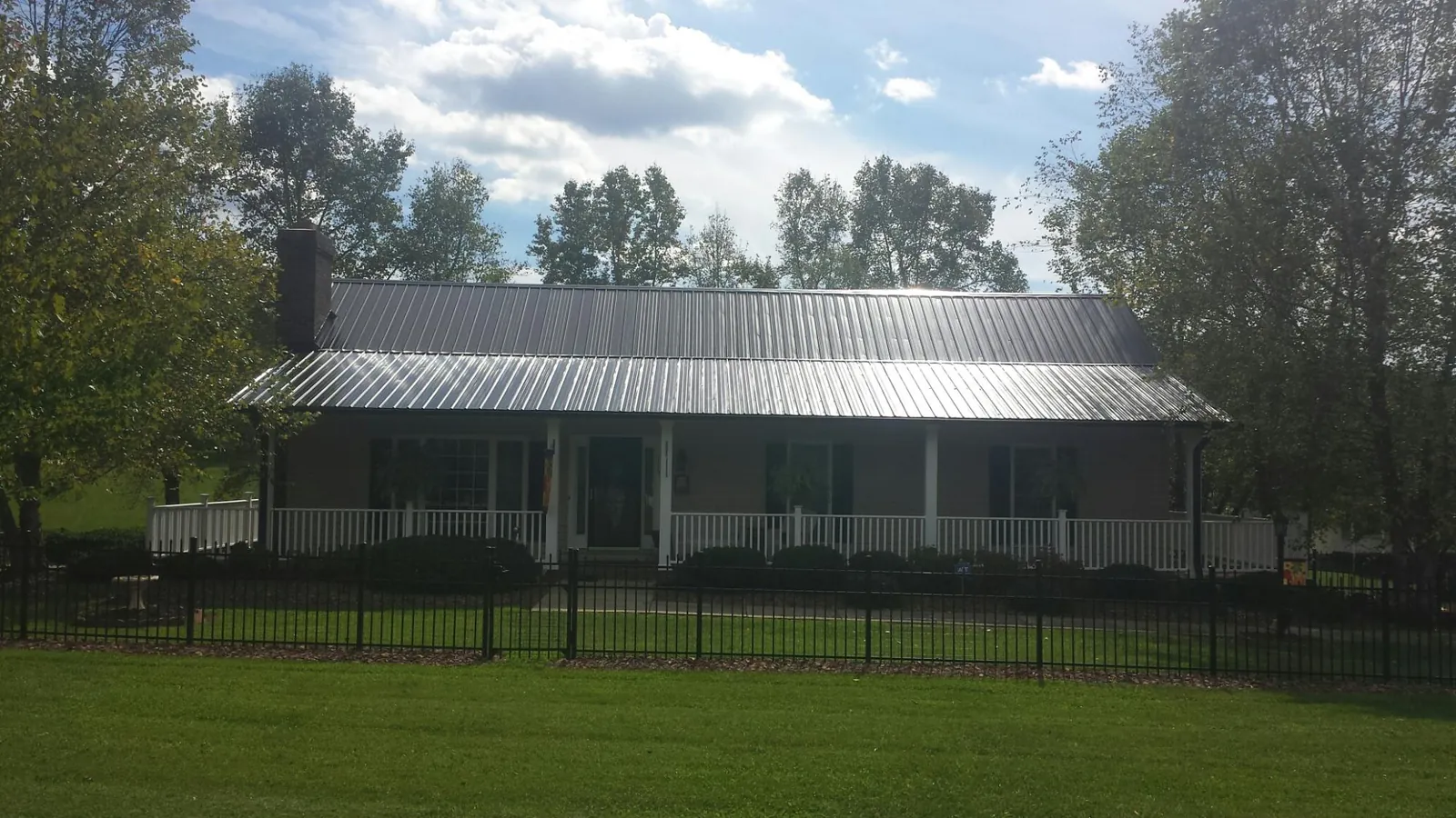 Gray metal roof on a brick ranch with a full width front porch — Gutter Guard Installation work by our crew in Wasco