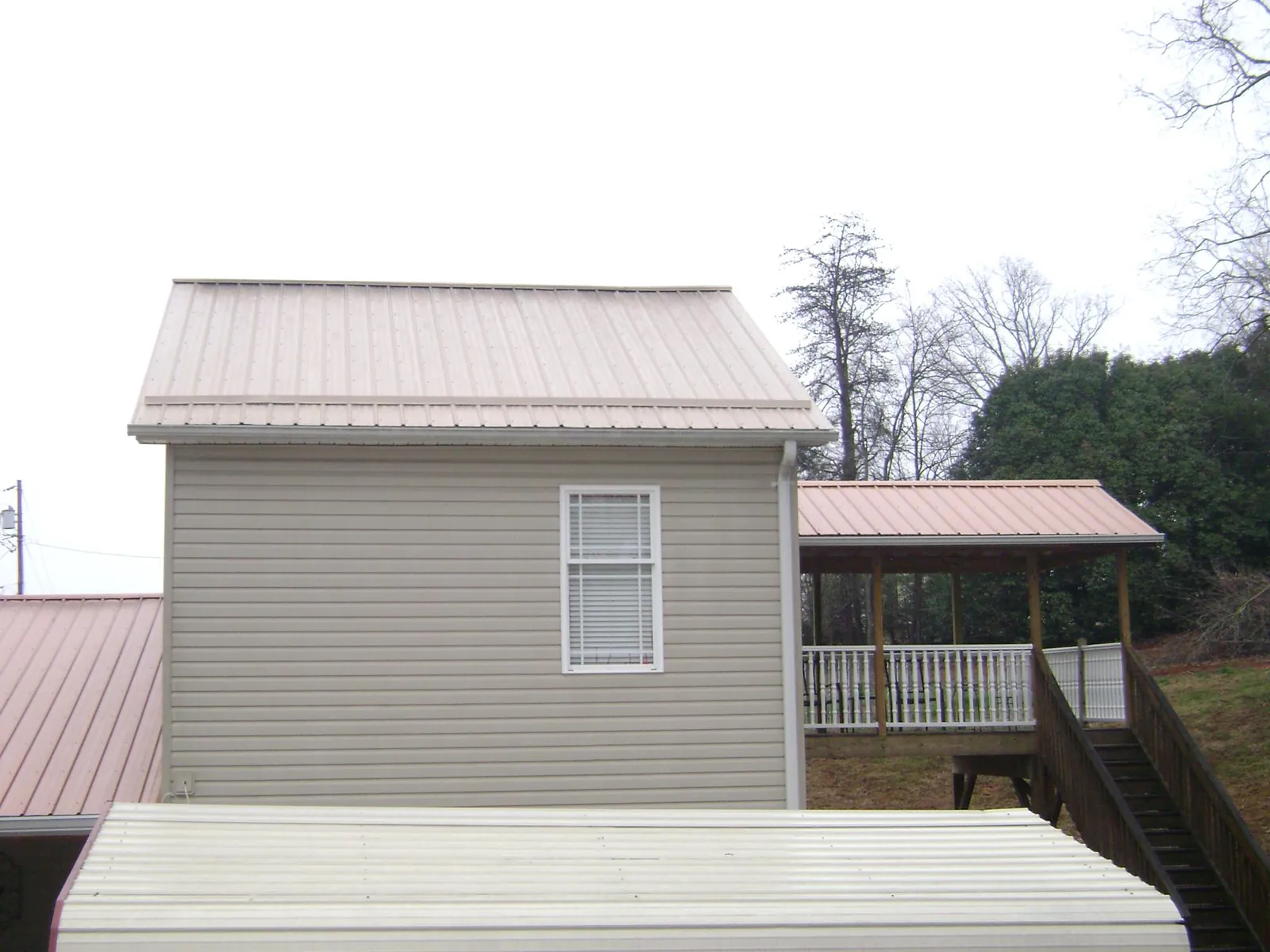Tan metal roofs on a two story addition and attached porch, from a Roof Replacement job in Wasco